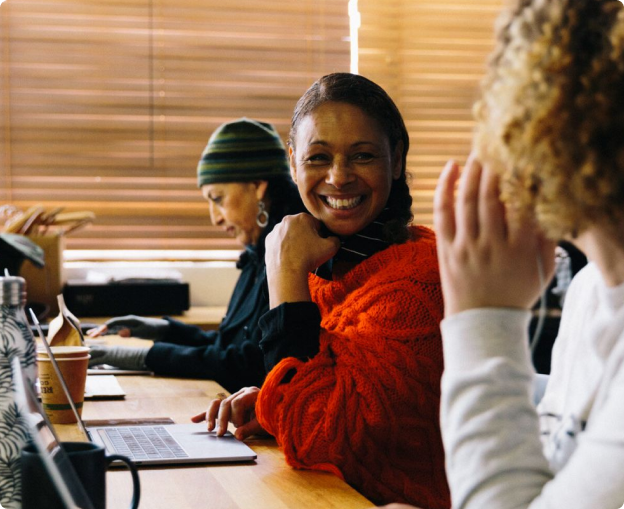 Smiling person sitting at a desk using a laptop, representing ease and productivity while using Grammarly's AI writing tools.